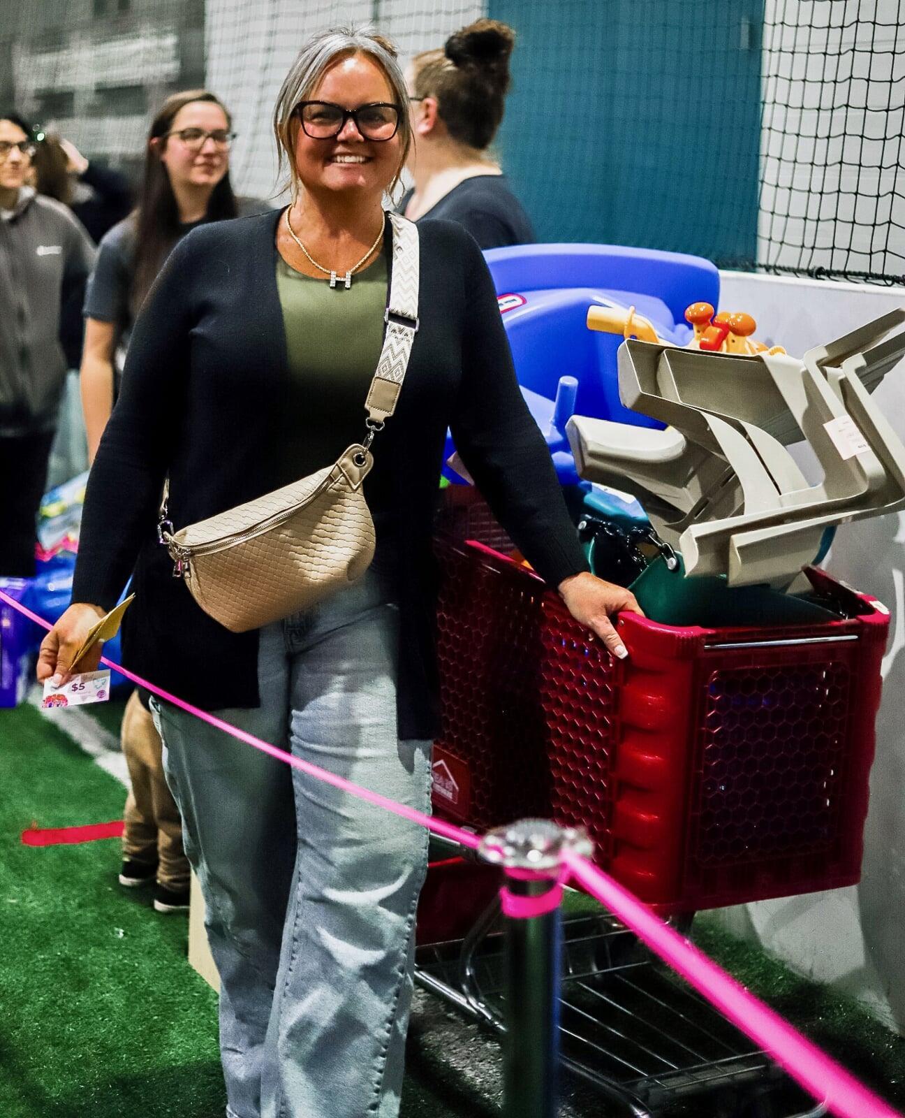Two women shopping. One is pulling a wagon and the other has a child in a backpack carrier.