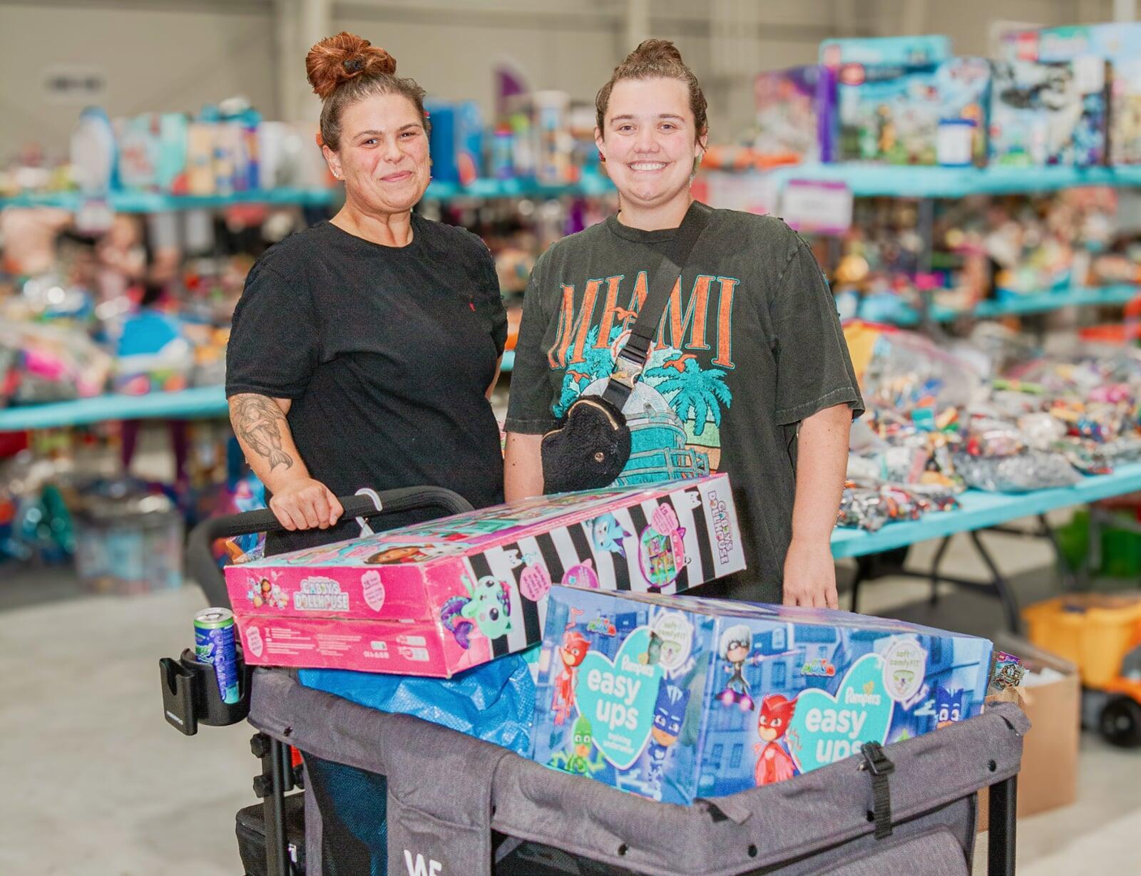 Two women stand by a wagon full of toys