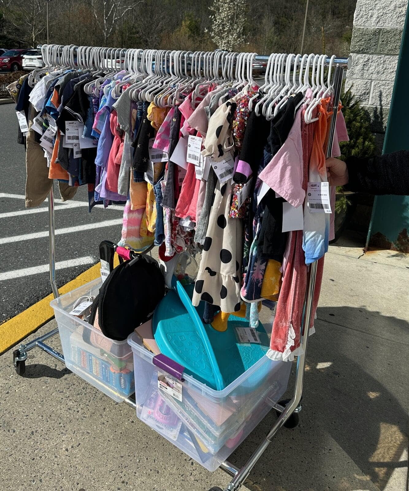 A rolling rack of clothing and other baby/children items in bins being wheeled into  the JBF sale at Body Zone in Wyomissing, PA.