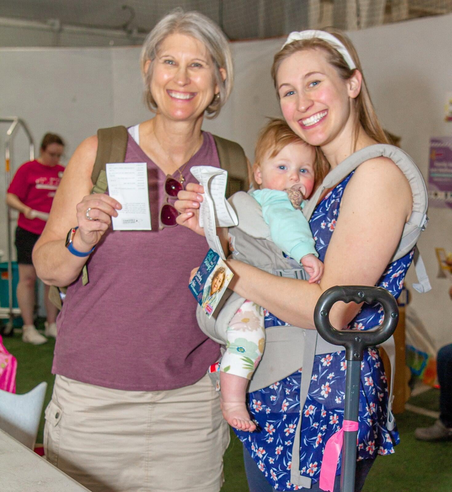 Two women shopping at the JBF sale. One is holding an infant.