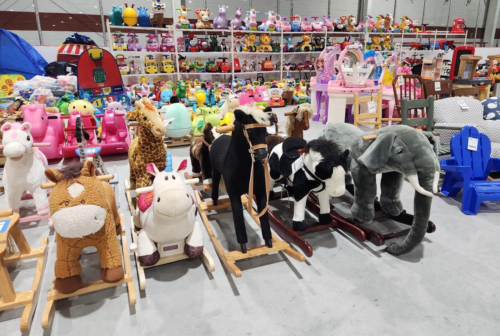 Rows of toddler ride on and other toys are organized on the floor and on shelves