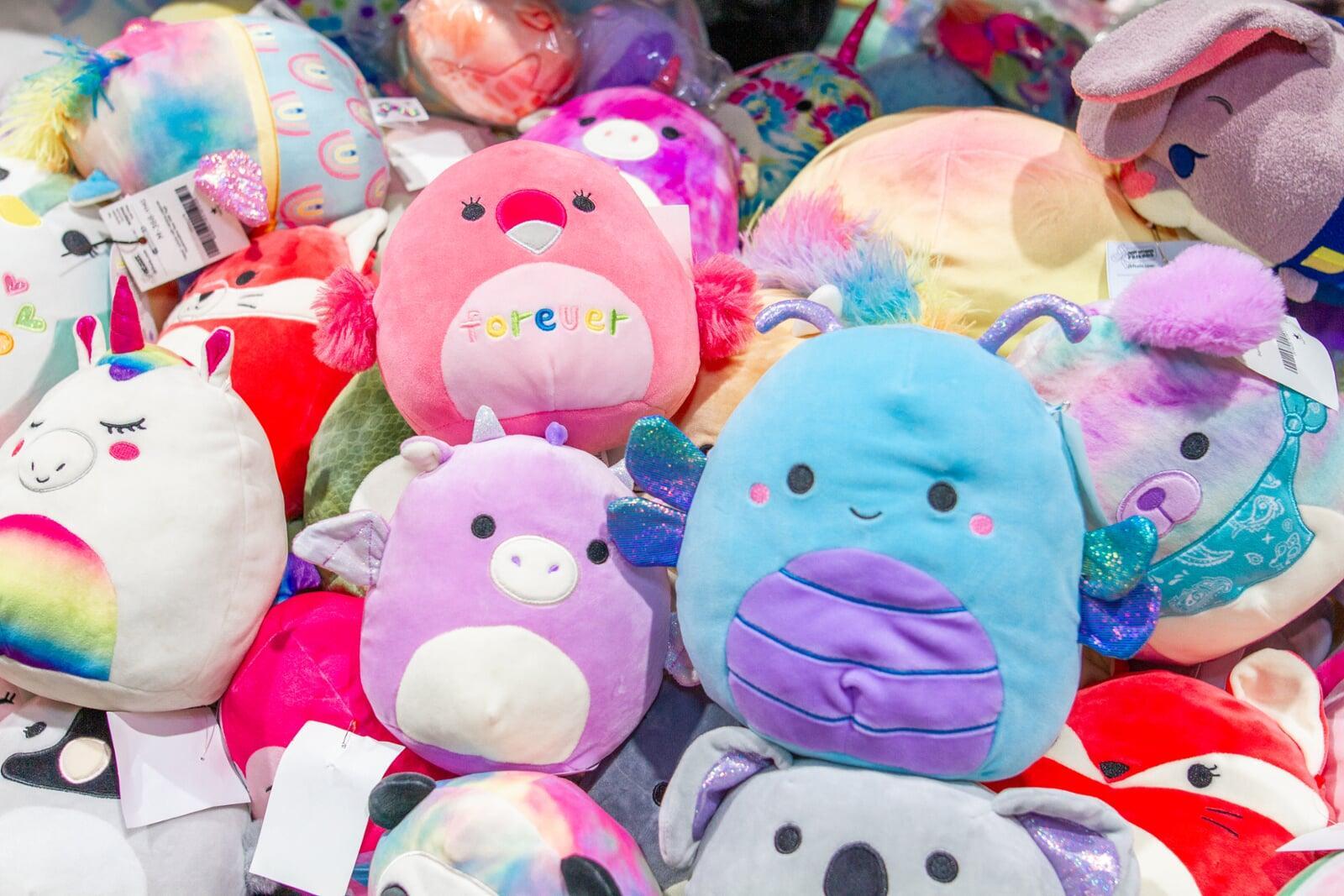 Squishmellos in all different colors are piled on a table together.