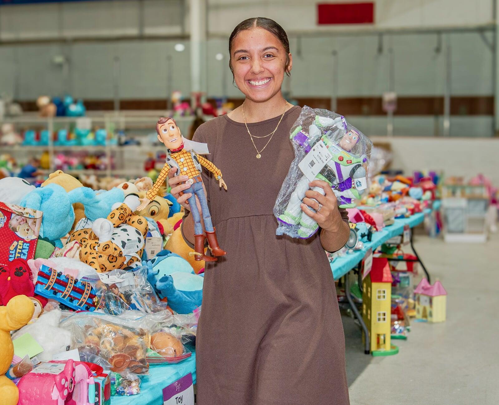 Woman wearing a brown dress is shopping and holding on to two toys
