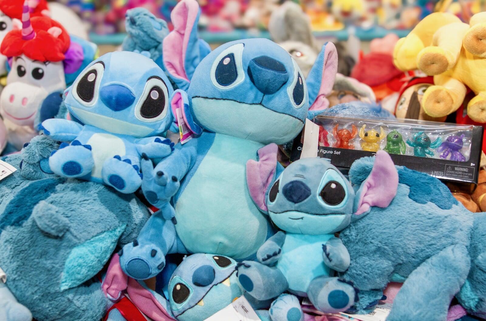 Many Stitch character plush toys and other plushes sitting on a table
