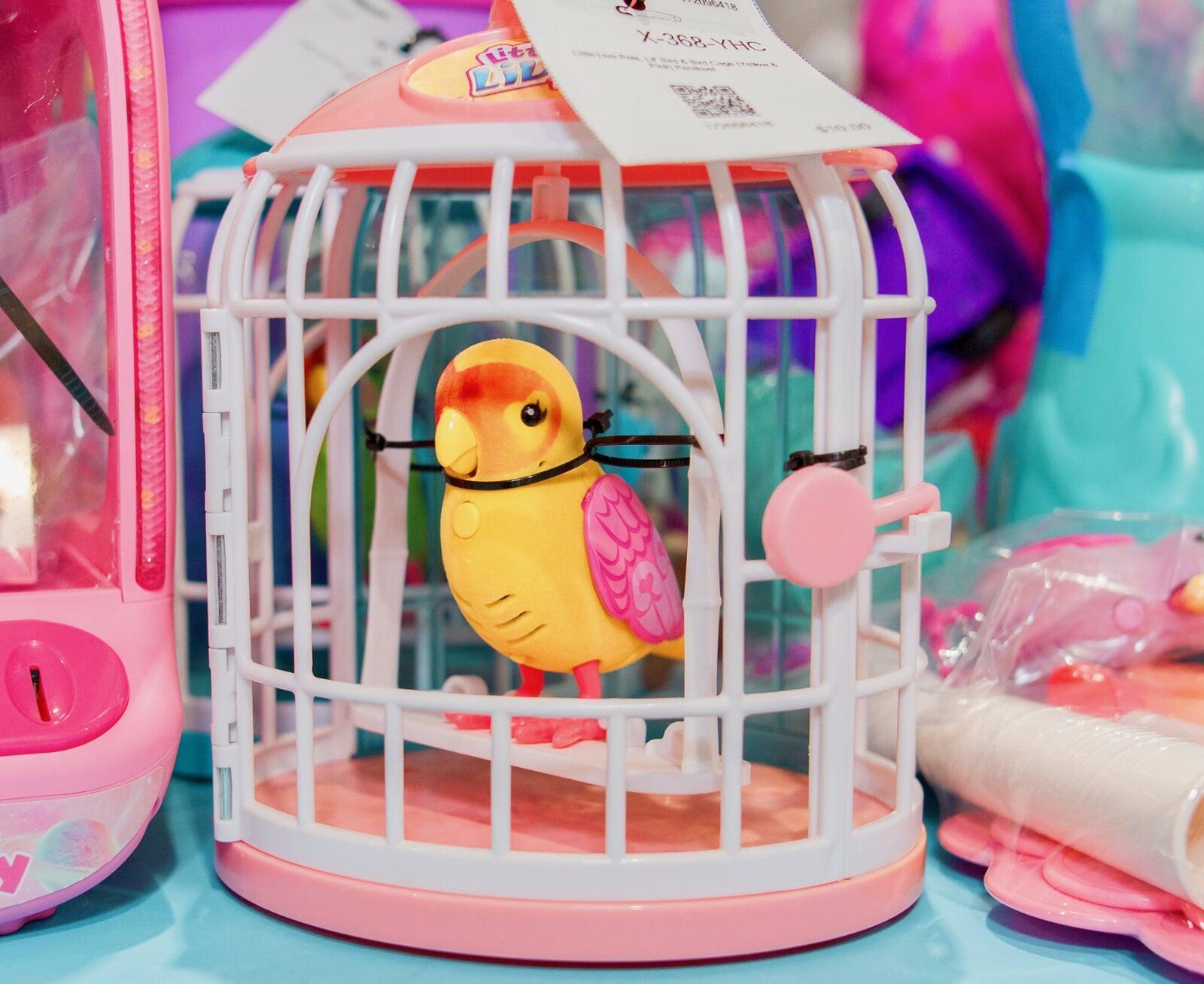 Toy yellow bird with pink wings in a cage